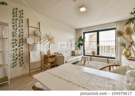 a living room with white furniture and plants in vases on the wall next to the dining table, there is a large window a living room with white furniture and plants in vases on the wall next to the dining table, there is a large window 104979617