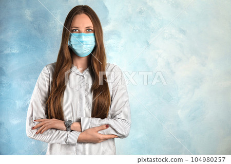 Woman with disposable mask on face against light blue background. Space for text Woman with disposable mask on face against light blue background. Space for text 104980257