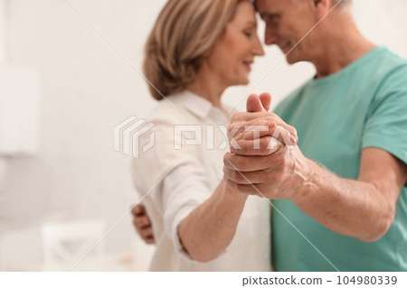 Happy senior couple dancing in kitchen, focus on hands Happy senior couple dancing in kitchen, focus on hands 104980339