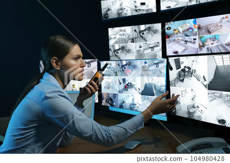 Security guard with portable transmitter monitoring modern CCTV cameras at night 104980428