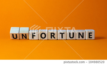 Fortune or unfortune symbol. Turned wooden cubes and changed the concept word unfortune to fortune. Beautiful orange table, orange background, copy space. Business, fortune or unfortune concept. 104980520