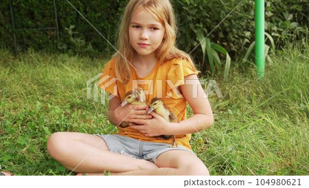 Cute teenage girl with ducklings on the lawn.  104980621