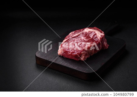 Fresh, raw beef steak with salt, spices and herbs 104980799