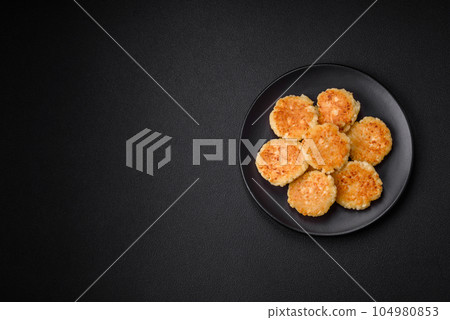 Delicious fresh cottage cheesecakes with raisins and vanilla on a black ceramic plate Delicious fresh cottage cheesecakes with raisins and vanilla on a black ceramic plate 104980853