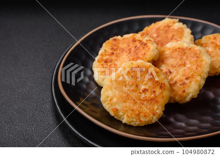 Delicious fresh cottage cheesecakes with raisins and vanilla on a black ceramic plate Delicious fresh cottage cheesecakes with raisins and vanilla on a black ceramic plate 104980872