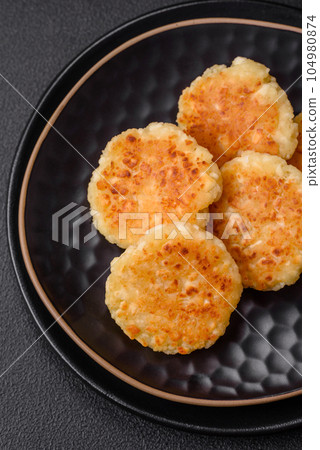 Delicious fresh cottage cheesecakes with raisins and vanilla on a black ceramic plate 104980874