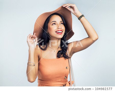Dressed for a sunny day. Studio shot of a stylish young woman standing against a white background. 104981577