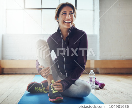 Fitness, music and stretching with a woman in her home, happy while sitting on an exercise mat. Workout, thinking and warm up with a happy young female athlete training for health or wellness 104981686