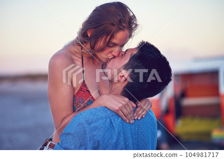 Kiss, love and couple at the beach on date, vacation or road trip in summer at sunset, together and romantic adventure. People, dating and support in relationship, happiness or boyfriend and girl 104981717