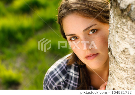 What a tree hugger. Shot of a beautiful young woman leaning against a tree in a forest. What a tree hugger. Shot of a beautiful young woman leaning against a tree in a forest. 104981752