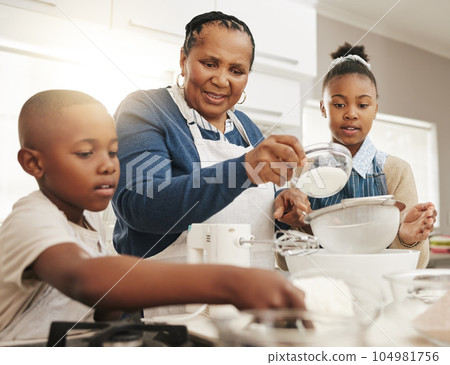 Black family, grandmother teaching kids baking and learning cooking skill in kitchen with help and support. Old woman with girl and boy, development with growth and bake with ingredients at home Black family, grandmother teaching kids baking and learning cooking skill in kitchen with help and support. Old woman with girl and boy, development with growth and bake with ingredients at home 104981756