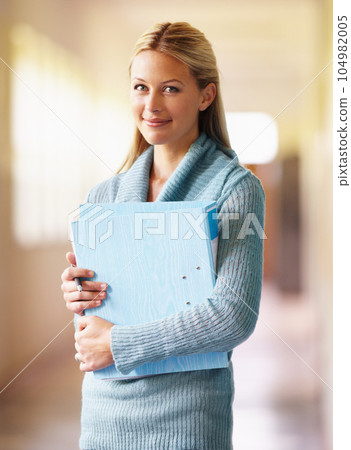 Portrait, teacher and woman in school with folder in hallway with pride for career or job. Education, documents and serious female educator in corridor ready for teaching or working in Australia. Portrait, teacher and woman in school with folder in hallway with pride for career or job. Education, documents and serious female educator in corridor ready for teaching or working in Australia. 104982005