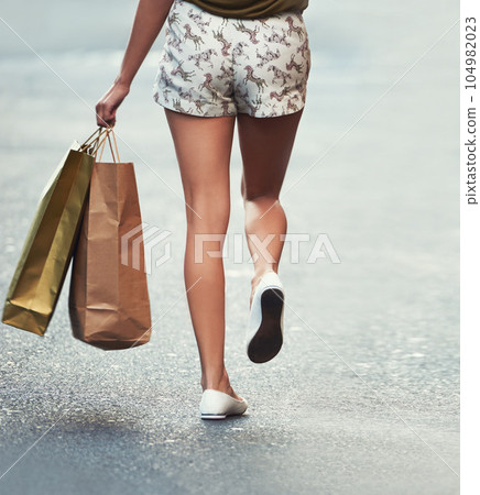 Shopping bag, street or legs of woman, walking and travel on urban city road after Black Friday discount. Retail, boutique fashion gift or back of customer with mall store purchase on concrete ground Shopping bag, street or legs of woman, walking and travel on urban city road after Black Friday discount. Retail, boutique fashion gift or back of customer with mall store purchase on concrete ground 104982023