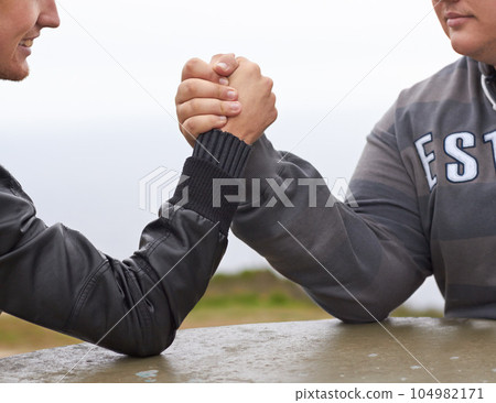 Hands, friends and competition with men and arm wrestling in nature for challenge, power and respect. Team, strong and conflict with closeup of people and holding hands for muscle, match and rival 104982171