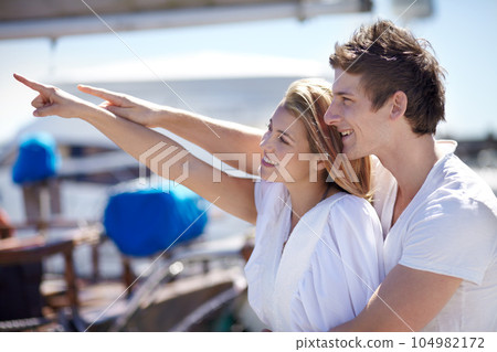 Happy, travel and couple point on yacht with smile on summer holiday, vacation and adventure on ocean. Love, travelling and man and woman pointing on luxury cruise for journey, romantic trip and fun 104982172