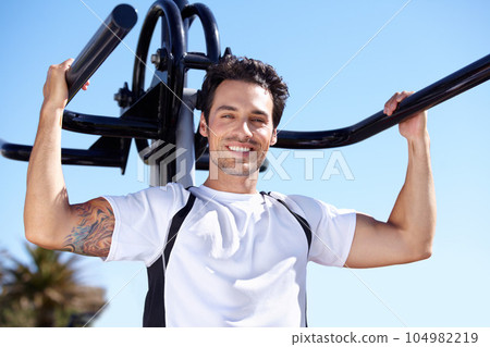 Happy man, fitness and portrait with equipment at park gym for workout, exercise or training in nature. Fit, active and strong male exercising on outdoor machine for strength or weightlifting Happy man, fitness and portrait with equipment at park gym for workout, exercise or training in nature. Fit, active and strong male exercising on outdoor machine for strength or weightlifting 104982219