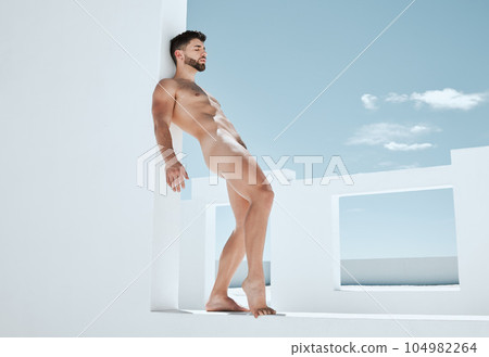 Creative, carefree and a man in the nude by a building for fantasy, freedom and handsome. Pose, art and a naked model standing by a wall in summer while attractive, sensual and seductive in nudity 104982264