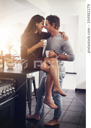Love, intimate and a couple kissing in the kitchen of their home together in the morning for romance. Kiss, passion or sexy with a man and woman in their house for romantic intimacy or bonding 104982279