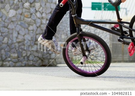 Legs, wheel and person on bicycle for trick, challenge and action at skatepark in city. Closeup, cycling stunt and urban biker in town with skill for balance, performance risk and freedom of motion Legs, wheel and person on bicycle for trick, challenge and action at skatepark in city. Closeup, cycling stunt and urban biker in town with skill for balance, performance risk and freedom of motion 104982811