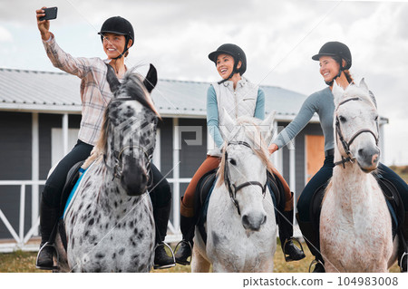 Smile, ladies. three attractive young women taking selfies while horse riding on a farm. 104983008