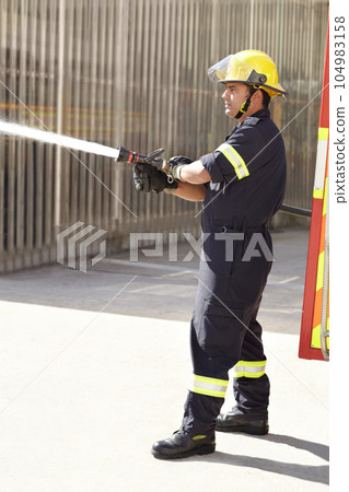 Male firefighter, spray water and emergency worker with helmet, uniform and brave to stop inferno. Fireman, fire hose and fearless on mission to rescue, health and safety service at job outdoor Male firefighter, spray water and emergency worker with helmet, uniform and brave to stop inferno. Fireman, fire hose and fearless on mission to rescue, health and safety service at job outdoor 104983158