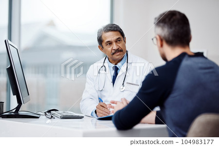 Healthcare, office and doctor in a consultation with a patient in discussion on a diagnosis in the clinic. Professional, career and mature male medical worker talking to man in the medicare hospital. 104983177