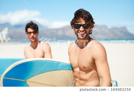 Beach, sea and man surfing friends outdoor together for travel, vacation or holiday trip overseas. Surf, summer or fun with a young male surfer in sunglasses and friend bonding on an ocean coast 104983250