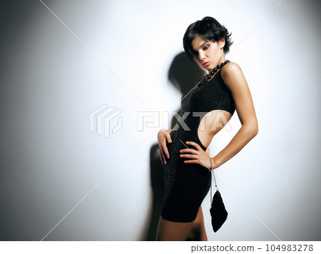 Fashion, spotlight and gen z girl in studio with attitude, style and cool while posing against wall background. Edgy, cool and fashionable female model relax in designer dress, beautiful and unique Fashion, spotlight and gen z girl in studio with attitude, style and cool while posing against wall background. Edgy, cool and fashionable female model relax in designer dress, beautiful and unique 104983278