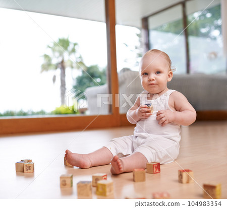 Portrait, baby and building blocks toy on a floor for fun, learning and playing in his home. Face, child and little boy with creative, alphabet and puzzle game in a living room, curious and sweet 104983354