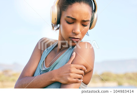 Young african american sportswoman suffering from shoulder pain while training. Woman holding her shoulder in pain while exercising outside. Overworking can lead to injury Young african american sportswoman suffering from shoulder pain while training. Woman holding her shoulder in pain while exercising outside. Overworking can lead to injury 104983414