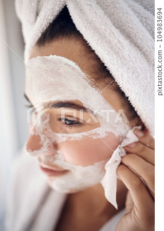 Facial, skincare and woman peeling a face mask for beauty in a grooming treatment with dermatology products. Relaxed, cream and young girl with tissue to wipe acne lotion cosmetics in a bathroom 104983694