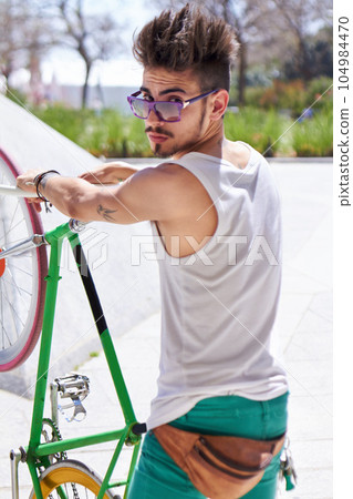 Man, cool style and portrait with bike in city, outdoor and sunglasses for unique street fashion. Young gen z guy, funky male hipster and cycling on bicycle in summer, urban town and with attitude 104984470