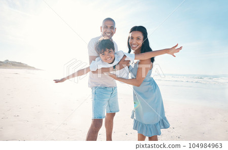 Adventure, beach and parents holding their kid on the sand by the ocean on a family vacation. Happy, smile and boy child flying and bonding with hid young mother and father on tropical summer holiday 104984963