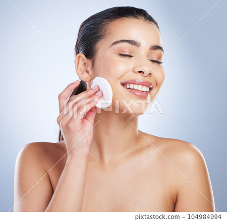 Skincare, pad and asian woman in studio for makeup removal, toner or hydration on grey background. Smile, beauty and asian lady wellness model with facial cotton for cleaning or glowing skin routine 104984994