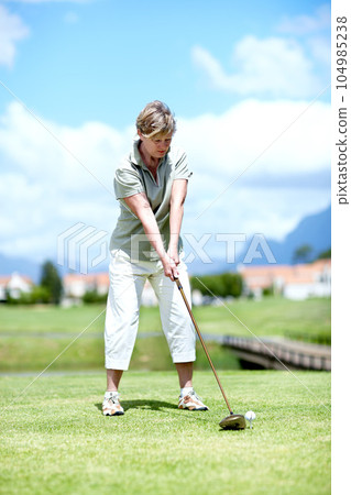 Senior, woman or golfer playing golf for fitness, workout or stroke exercise on a course in retirement. Mature, golfing or serious lady player training in sports game driving with her club or driver 104985238