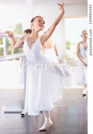 Girl ballerina pose at barre, ballet and dance class with young dancer learning balance and art at studio. Female child in lesson at academy, creativity with fitness and training, elegance and focus Girl ballerina pose at barre, ballet and dance class with young dancer learning balance and art at studio. Female child in lesson at academy, creativity with fitness and training, elegance and focus 104985445