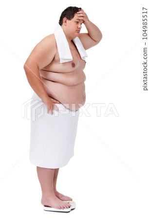 Body, plus size and man on a scale in studio with stress or frustration after diet or exercise failure. Upset, weight loss and male person with towel weighing on machine isolated by white background. Body, plus size and man on a scale in studio with stress or frustration after diet or exercise failure. Upset, weight loss and male person with towel weighing on machine isolated by white background. 104985517