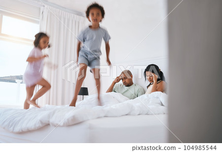 Young kids, jump and parents on bed with playing, game and excited in family house in morning. Naughty sibling children, mother and father in bedroom with bond, love and childhood development in home 104985544