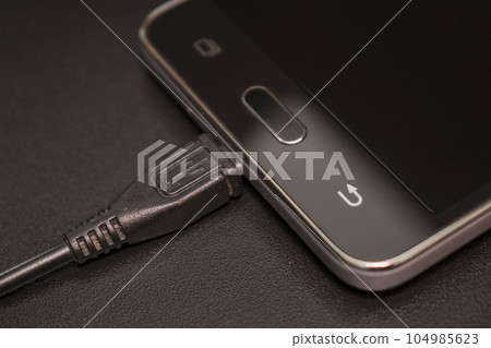 black smartphone with black charger on black background black smartphone with black charger on black background 104985623