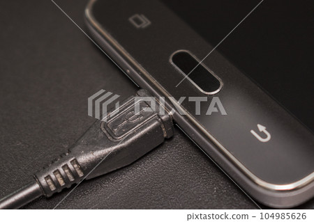 black smartphone with black charger on black background black smartphone with black charger on black background 104985626