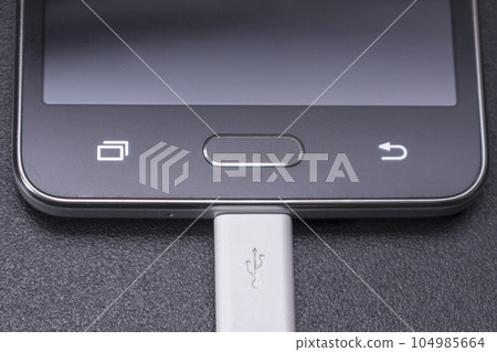 black smartphone on black background with white cable 104985664