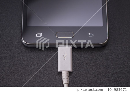 black smartphone on black background with white cable 104985671