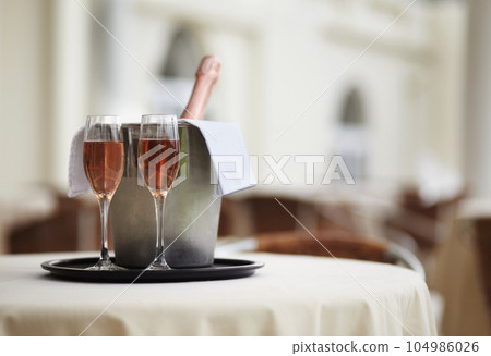 Restaurant, bottle and glasses of champagne on a table for luxury service, celebration and hospitality. Hotel, wealth and wine, alcohol and drinks at a fine dining establishment for an experience 104986026