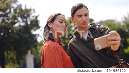Selfie, happy and women or friends outdoor for social media update, influencer post or digital memory with emoji face. Young, gen z people in profile picture or photography online and peace hand sig 104986122