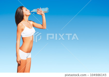 Fitness, woman and drinking water on mockup space for hydration after workout, exercise or training on blue sky. Thirsty, active and fit female with drink bottle for healthy body, wellness or hydrate Fitness, woman and drinking water on mockup space for hydration after workout, exercise or training on blue sky. Thirsty, active and fit female with drink bottle for healthy body, wellness or hydrate 104986143