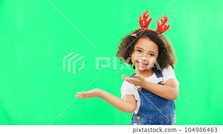 Christmas, green screen and a girl presenting advertising space for product placement in studio. Portrait, kids or celebration with an adorable little child on chromakey mockup for the festive season Christmas, green screen and a girl presenting advertising space for product placement in studio. Portrait, kids or celebration with an adorable little child on chromakey mockup for the festive season 104986463