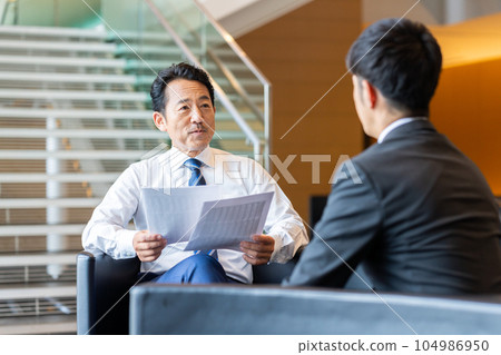 Middle-aged businessman having a business meeting Middle-aged businessman having a business meeting 104986950
