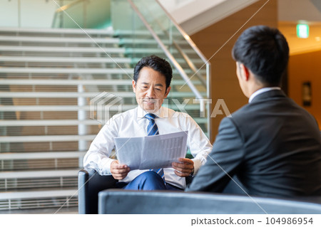 Middle-aged businessman having a business meeting Middle-aged businessman having a business meeting 104986954