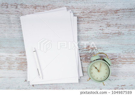 The Top view of heap empty A4 paper and vintage alarm on wooden background for your text or message. The Top view of heap empty A4 paper and vintage alarm on wooden background for your text or message. 104987589