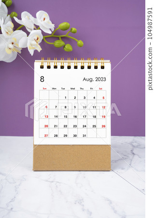 The August 2023 calendar desk and white orchid on purple background. The August 2023 calendar desk and white orchid on purple background. 104987591